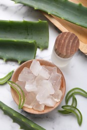 Photo of Aloe vera gel, bottle and slices of plant on white marble table, flat lay