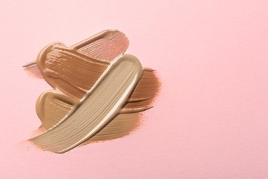 Image of Different shades of liquid foundation on pink background, top view. Space for text 