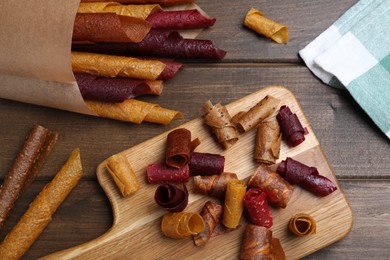 Delicious fruit leather rolls on wooden table, flat lay