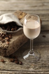 Coffee cream liqueur in glass and beans on wooden table