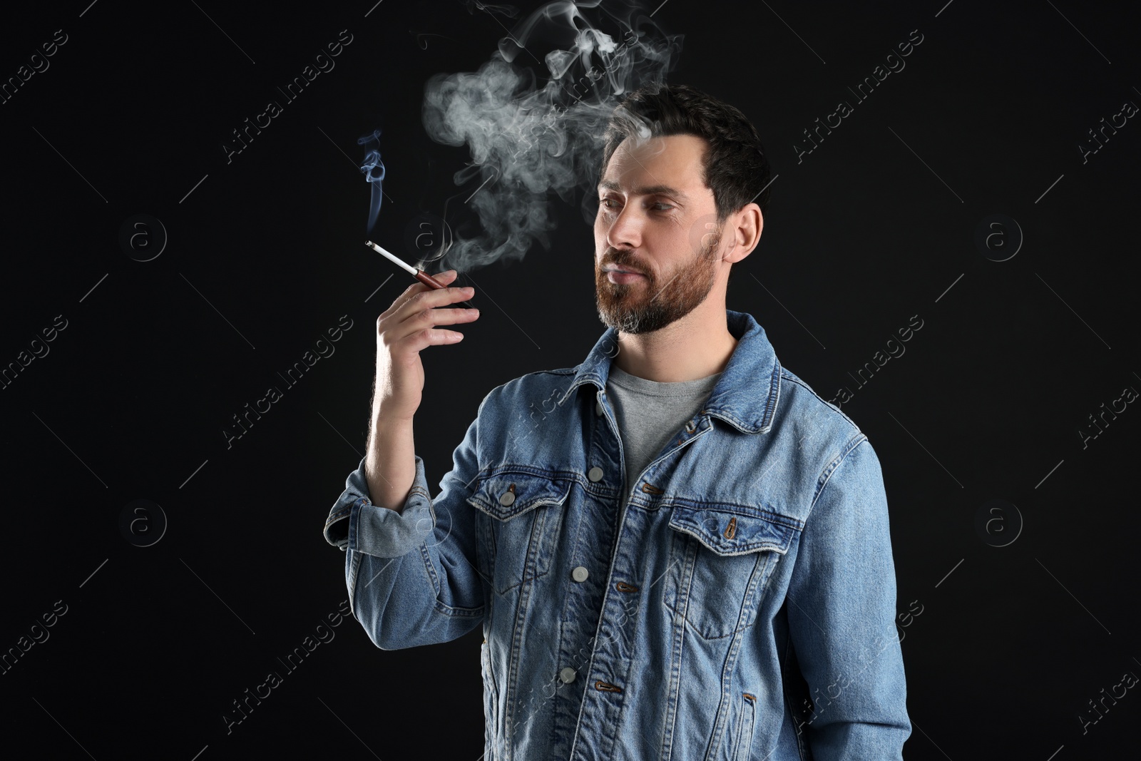 Photo of Man using cigarette holder for smoking on black background, space for text