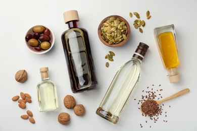 Photo of Vegetable fats. Different oils in glass bottles and ingredients on white table, flat lay