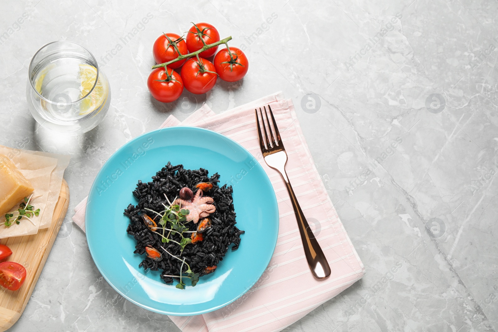 Photo of Delicious black risotto with seafood served on marble table, flat lay