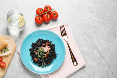 Delicious black risotto with seafood served on marble table, flat lay