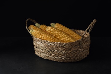 Corn cobs in basket on black table