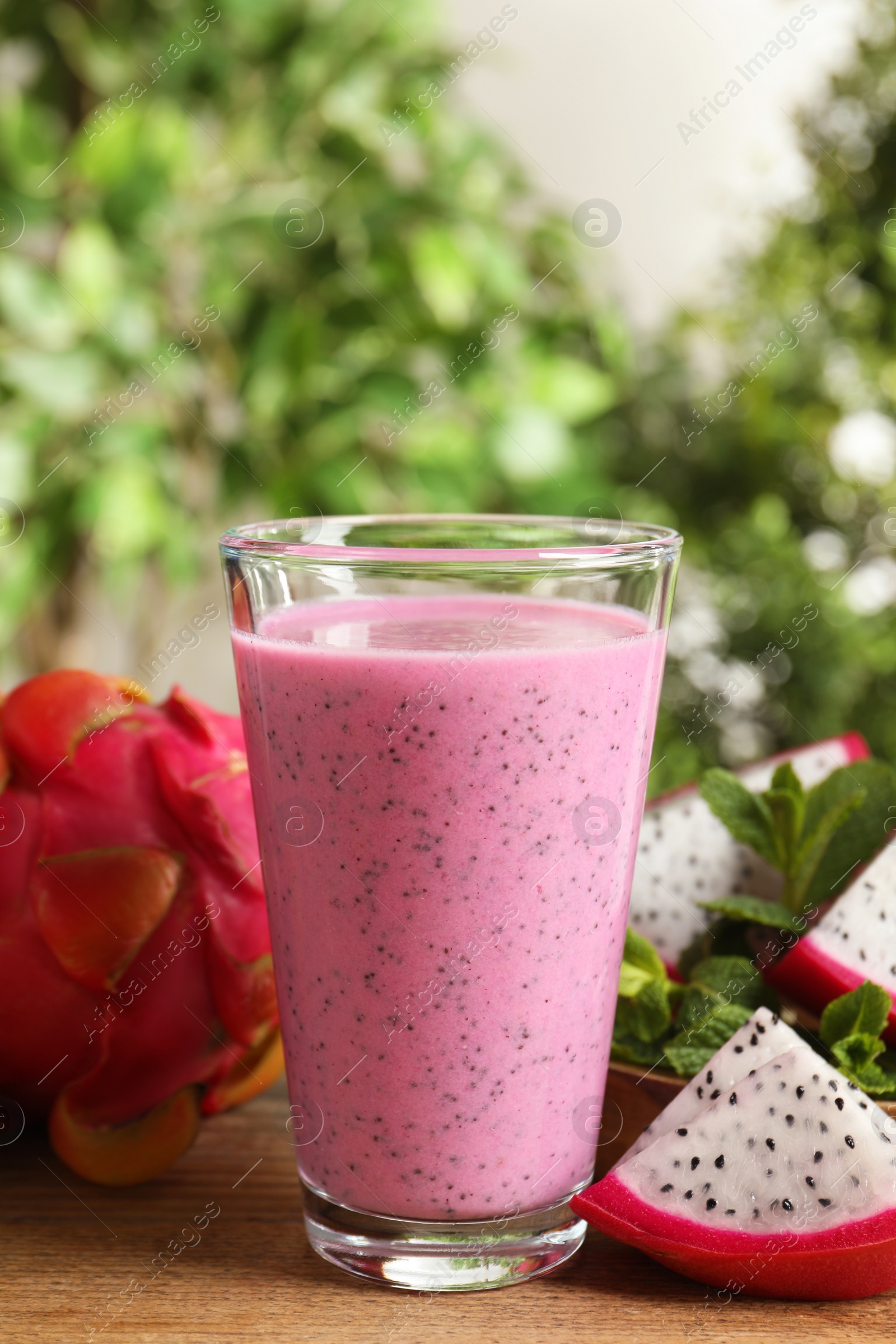 Photo of Delicious pitahaya smoothie and fresh fruits on wooden table