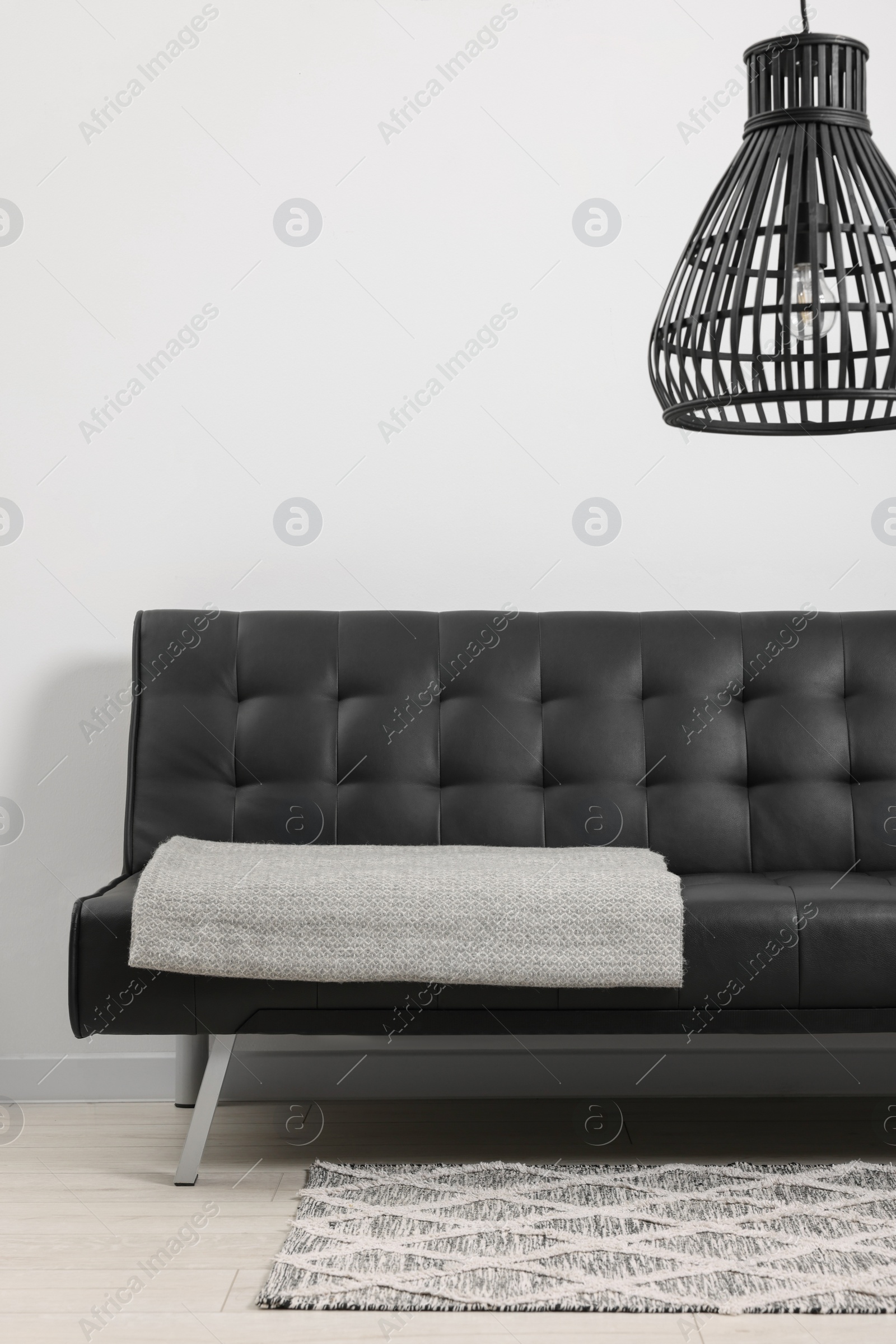 Photo of Comfortable sofa with grey blanket in living room