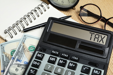 Image of Calculator with word Tax, money and stationery on table, closeup