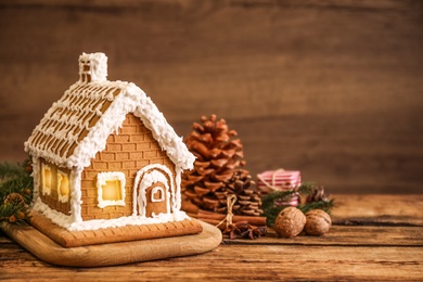 Photo of Beautiful gingerbread house decorated with icing on wooden table