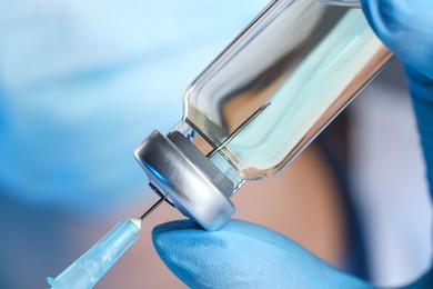 Photo of Doctor filling syringe with medication from glass vial, closeup