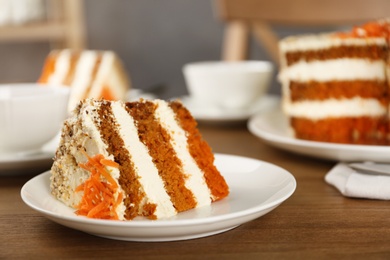 Photo of Plate with piece of carrot cake on wooden table, space for text