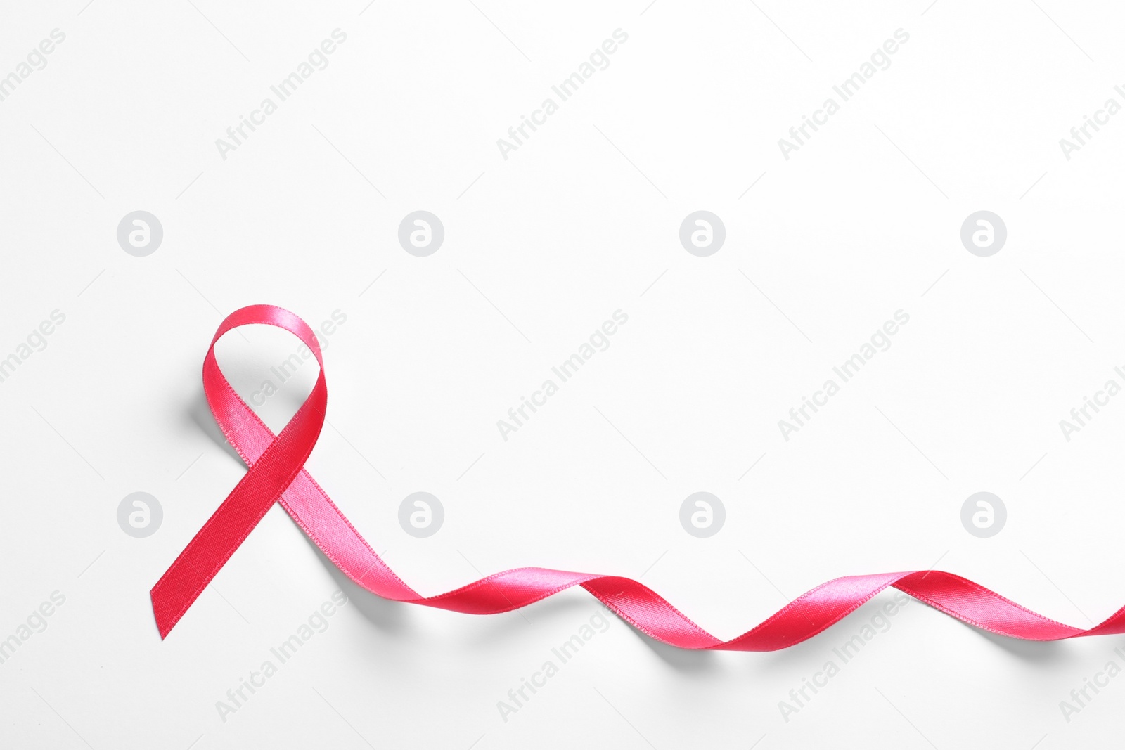 Photo of Pink ribbon on white background, top view. Cancer awareness