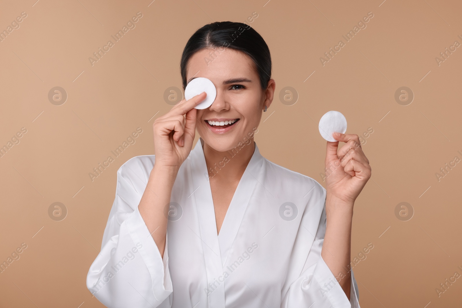 Photo of Young woman with cotton pads on beige background