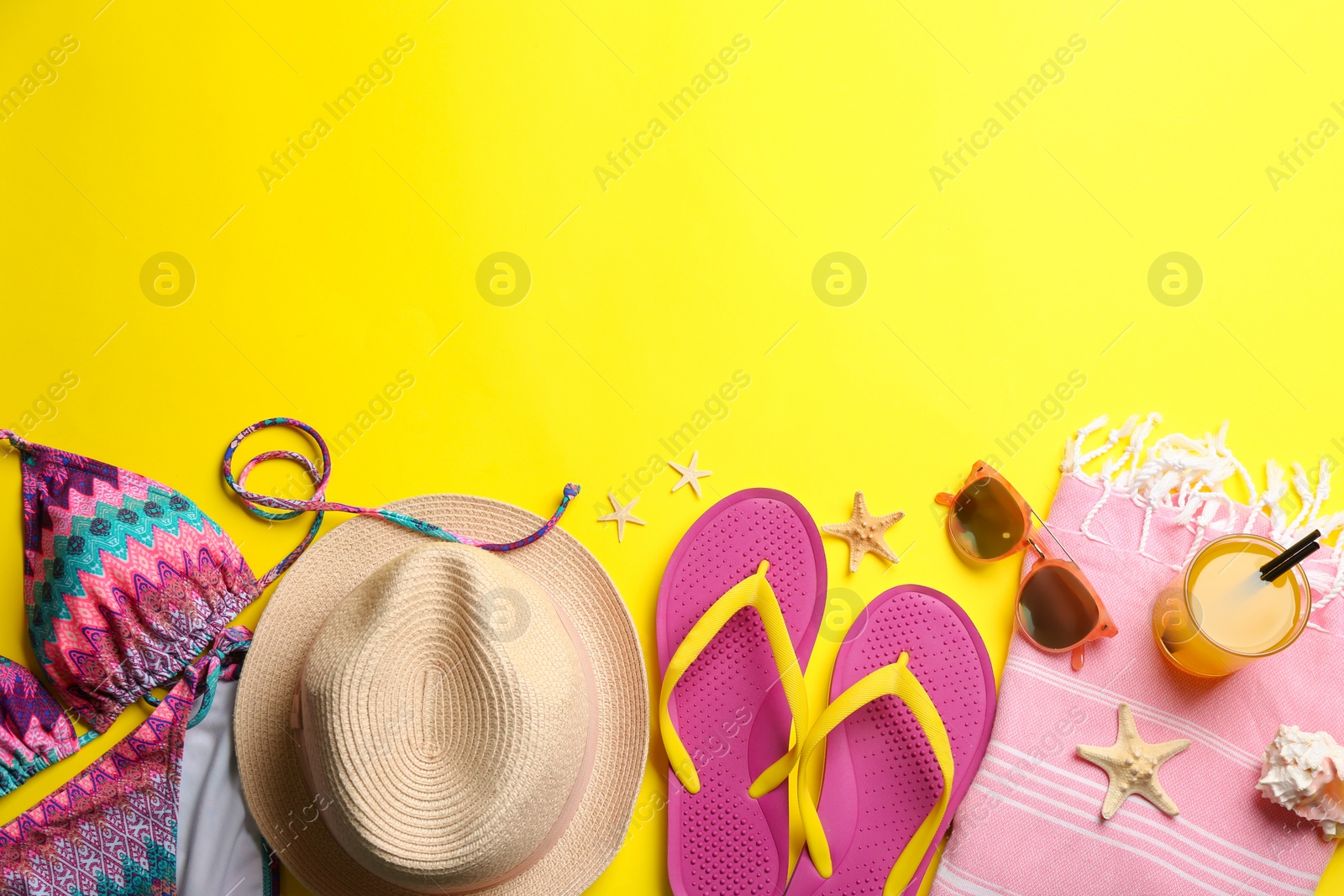 Photo of Beach accessories on yellow background, flat lay. Space for text