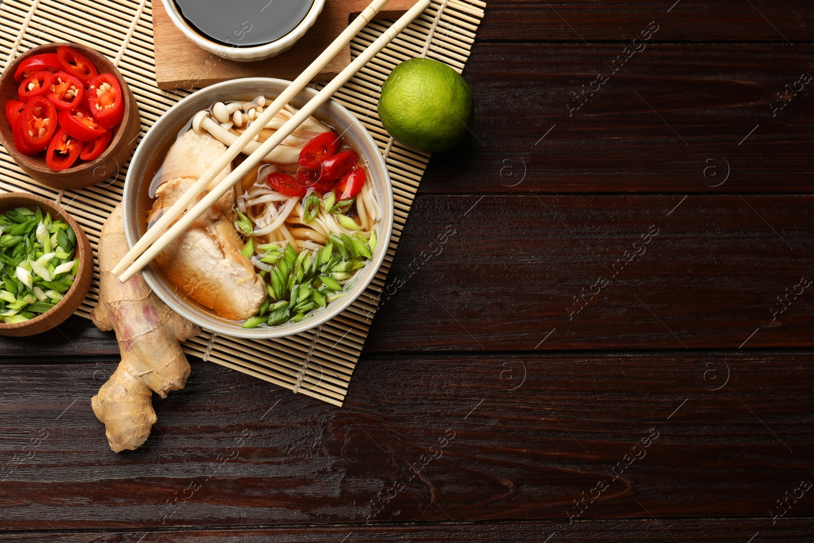 Photo of Delicious ramen with meat and ingredients on wooden table, flat lay. Space for text