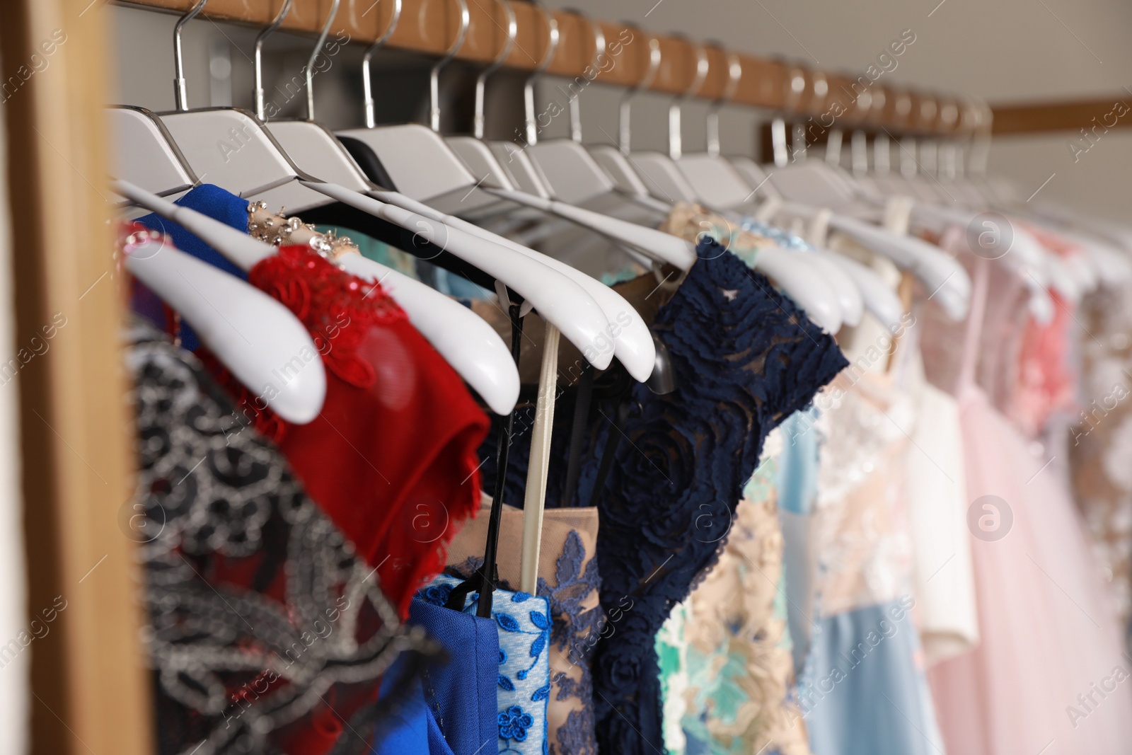 Photo of Different beautiful dresses on hangers in rental clothing salon