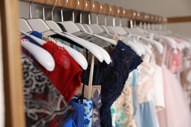 Photo of Different beautiful dresses on hangers in rental clothing salon