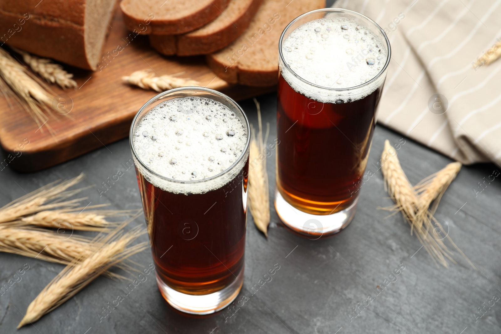 Photo of Glasses of delicious kvass, bread and spikes on black table