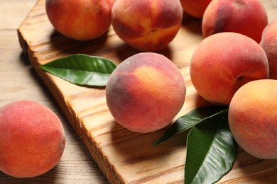 Photo of Fresh peaches and leaves on wooden table, closeup