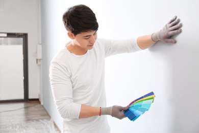 Male decorator holding color palette samples on white background