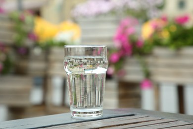 Photo of Glass of fresh water on wooden table outdoors