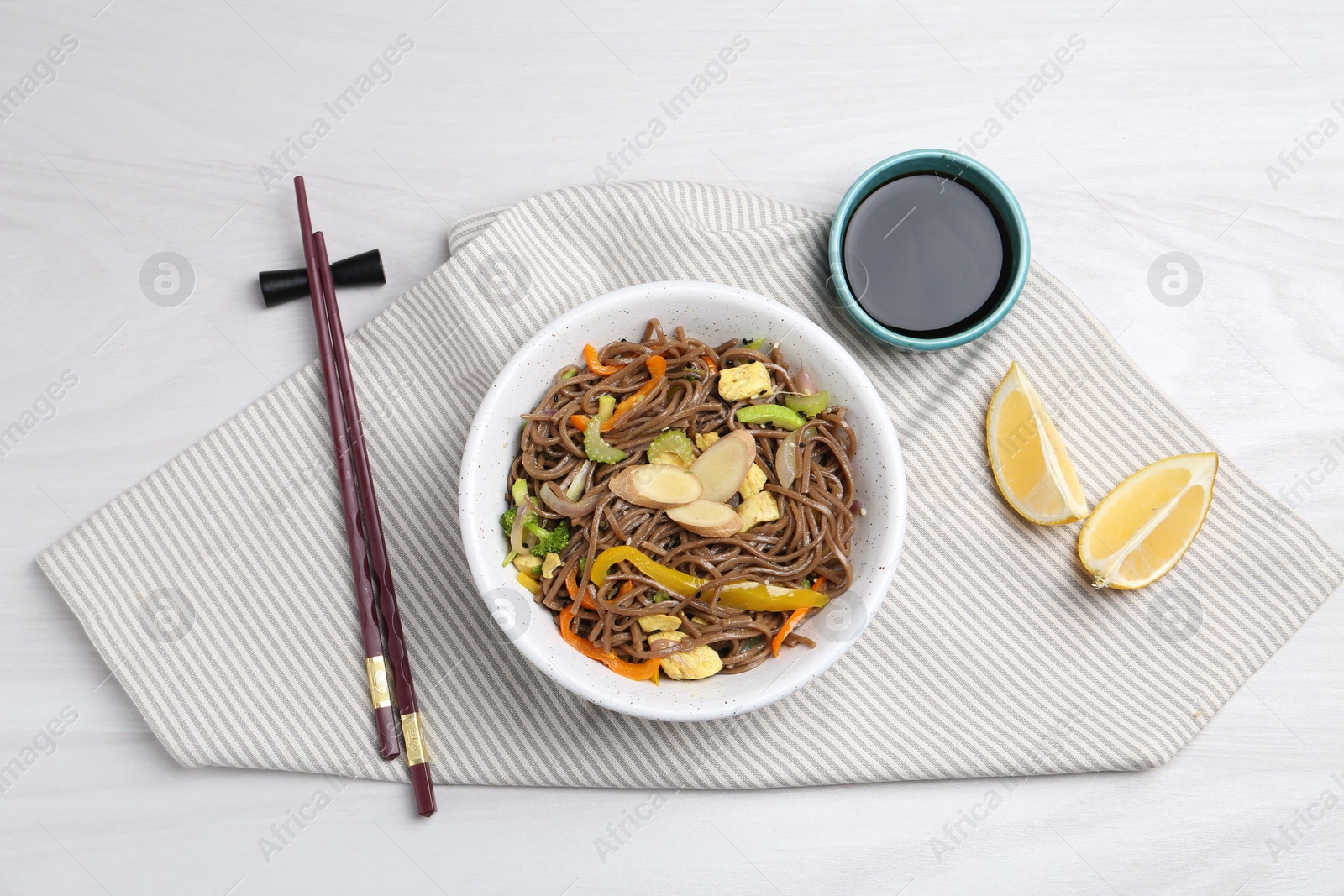 Photo of Stir-fry. Delicious cooked noodles with chicken and vegetables in bowl served on light wooden table, flat lay