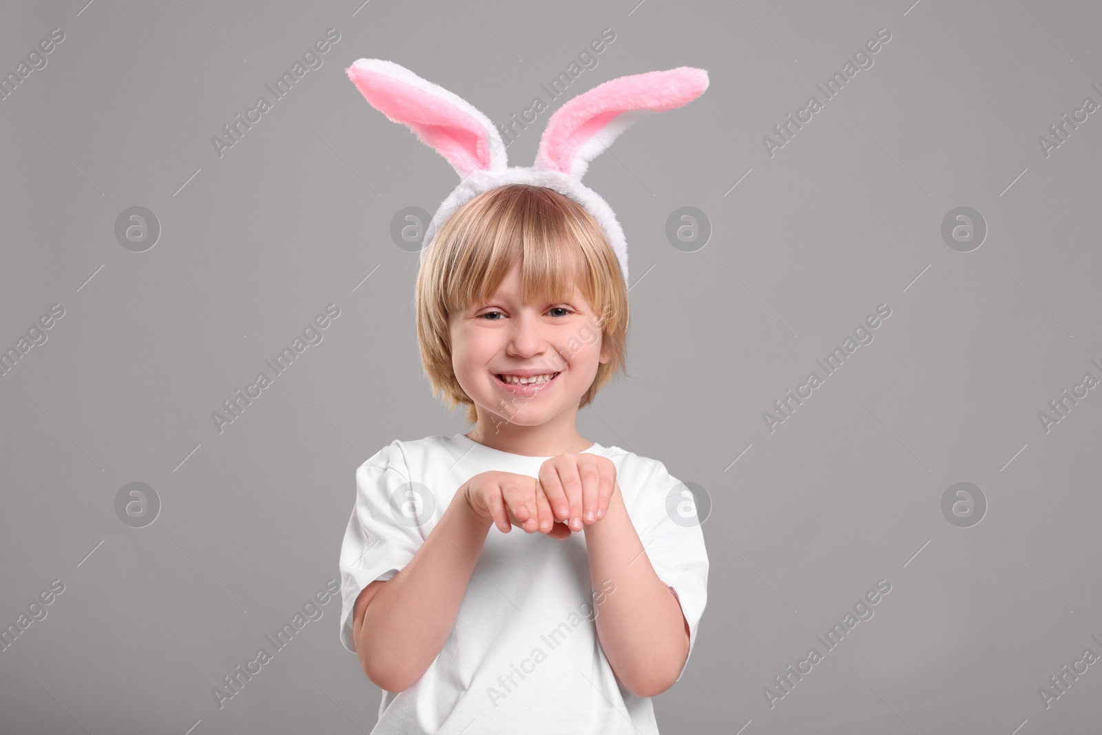 Photo of Happy boy wearing bunny ears headband on grey background. Easter celebration