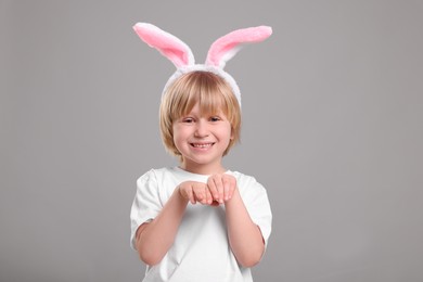 Happy boy wearing bunny ears headband on grey background. Easter celebration