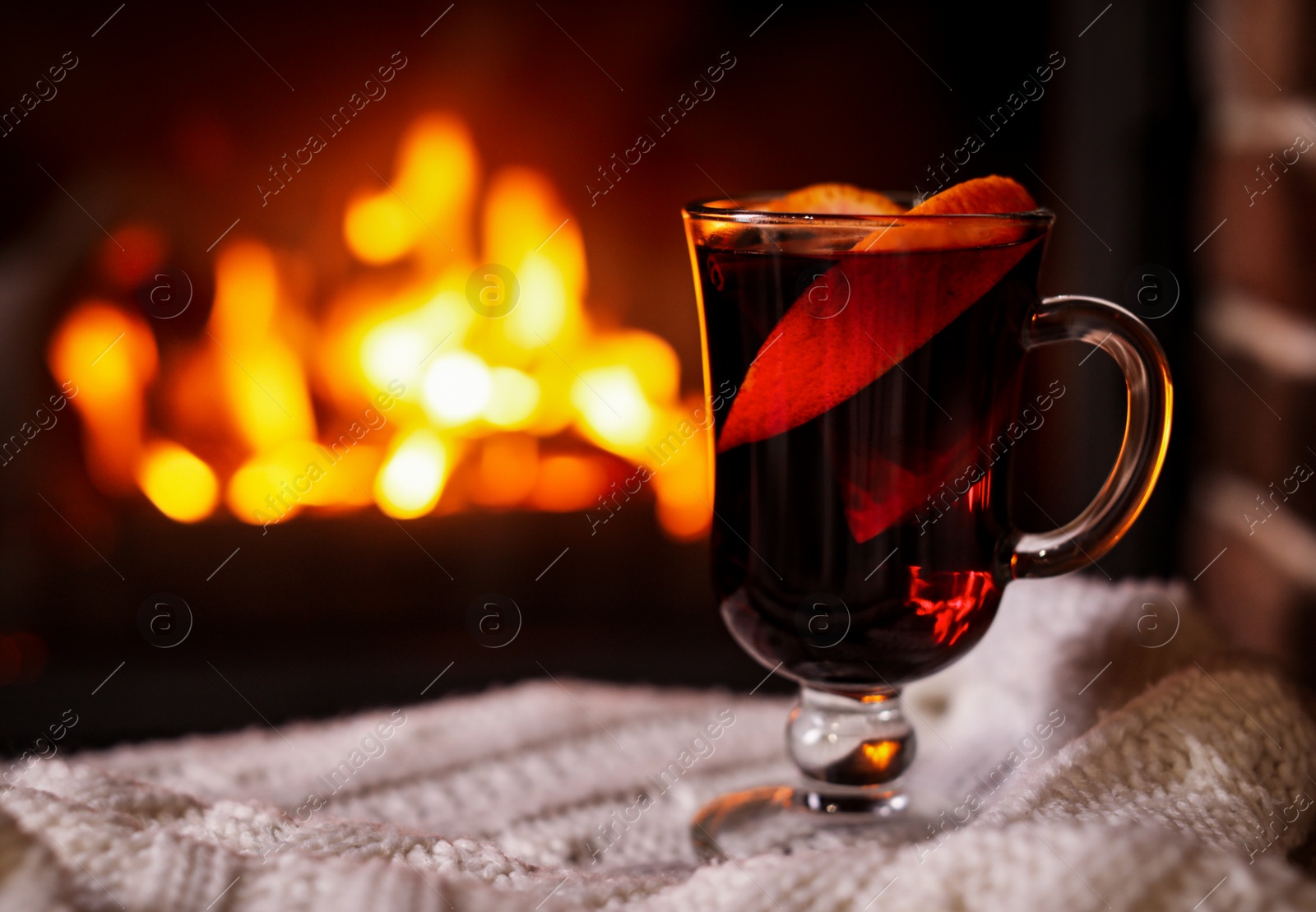 Photo of Delicious mulled wine and blurred fireplace on background