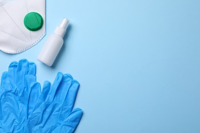 Photo of Hand sanitizer, medical gloves and respirator on light blue background, flat lay. Space for text