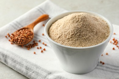 Photo of Bowl of flour and spoon with buckwheat on cloth