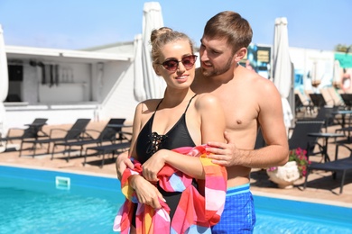 Happy young couple near swimming pool at resort