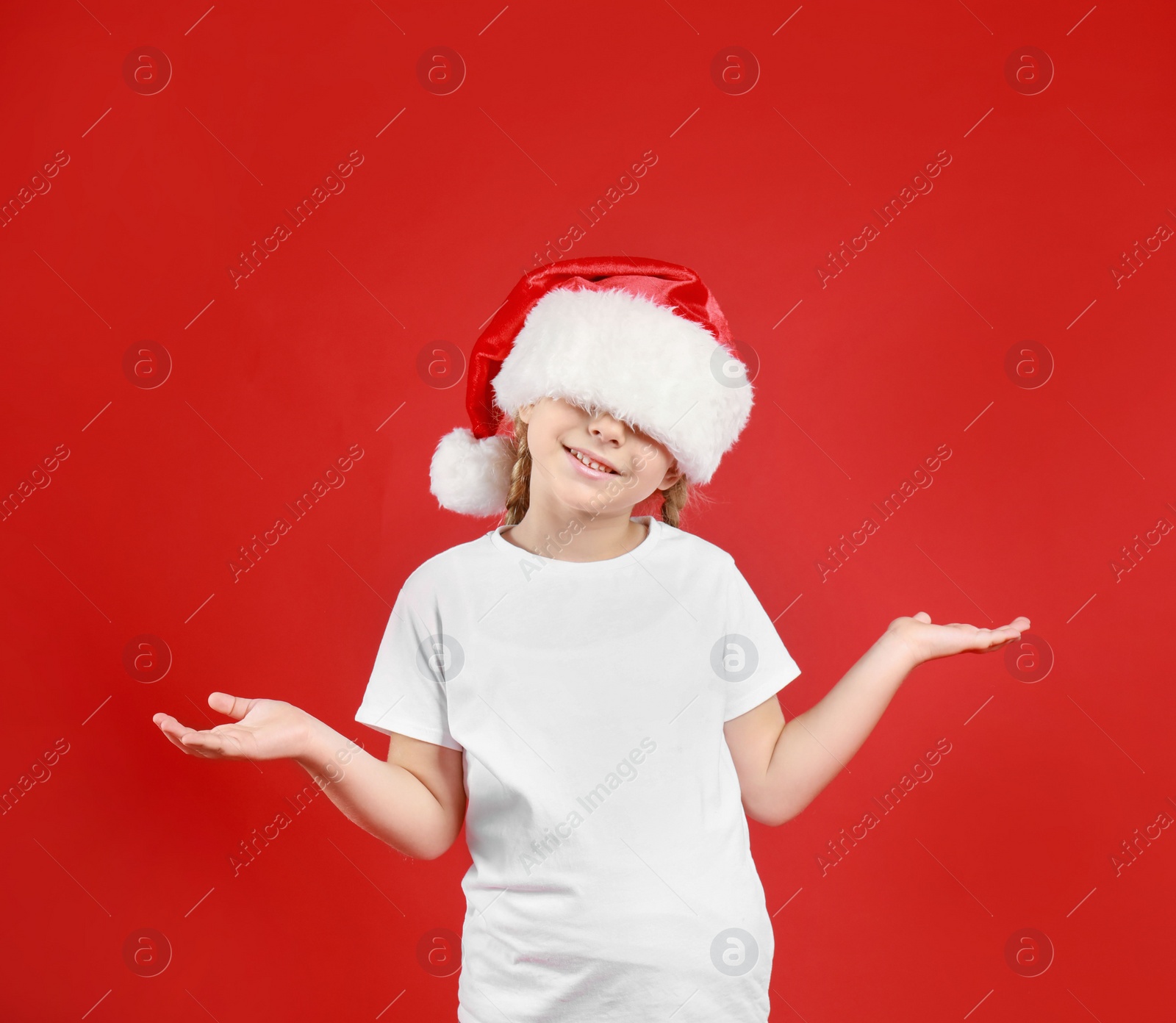 Photo of Cute little child wearing Santa hat on red background. Christmas holiday