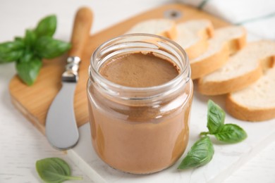 Delicious meat pate, fresh bread, knife and basil on white wooden table, closeup