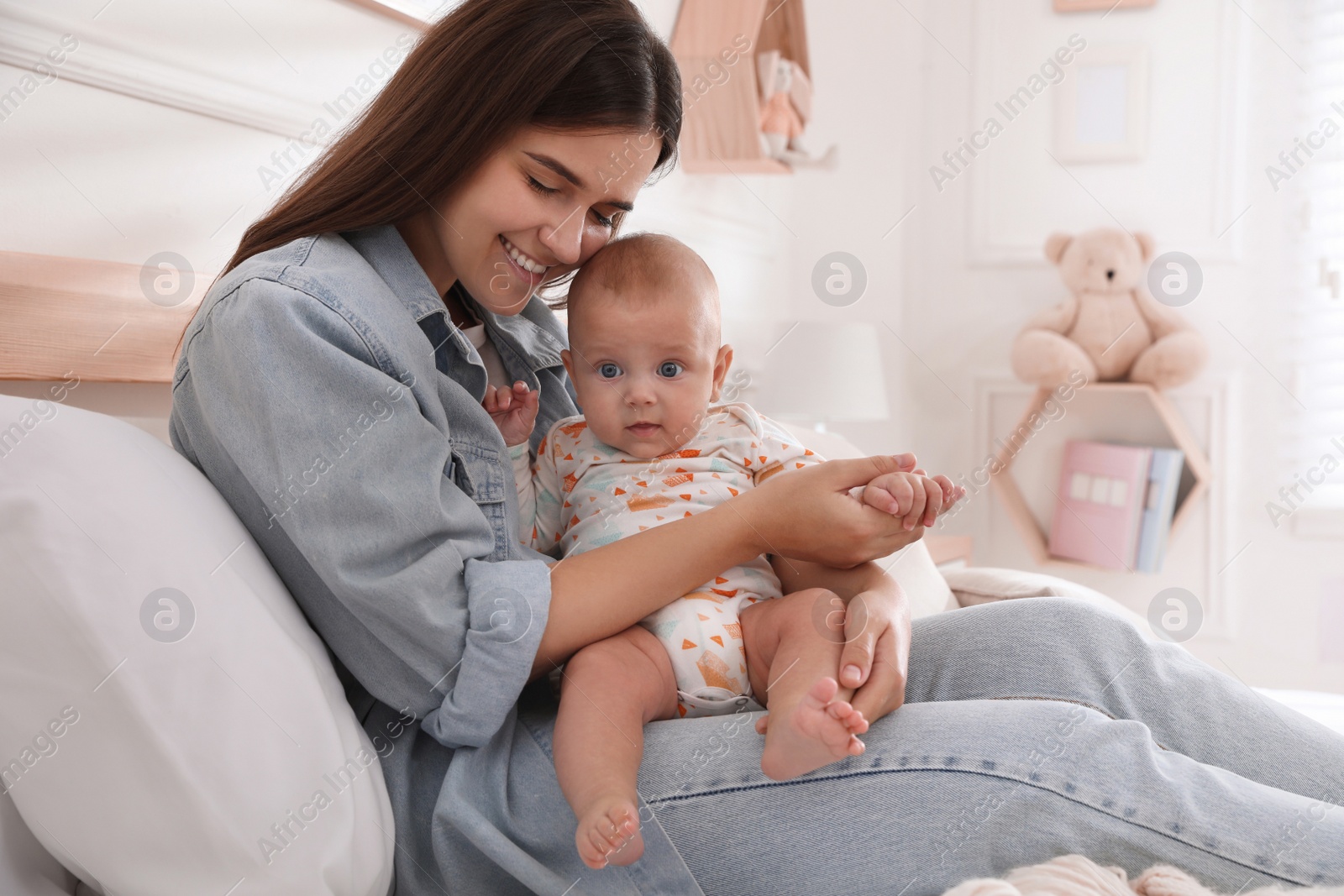 Photo of Mother with her cute baby on bed at home