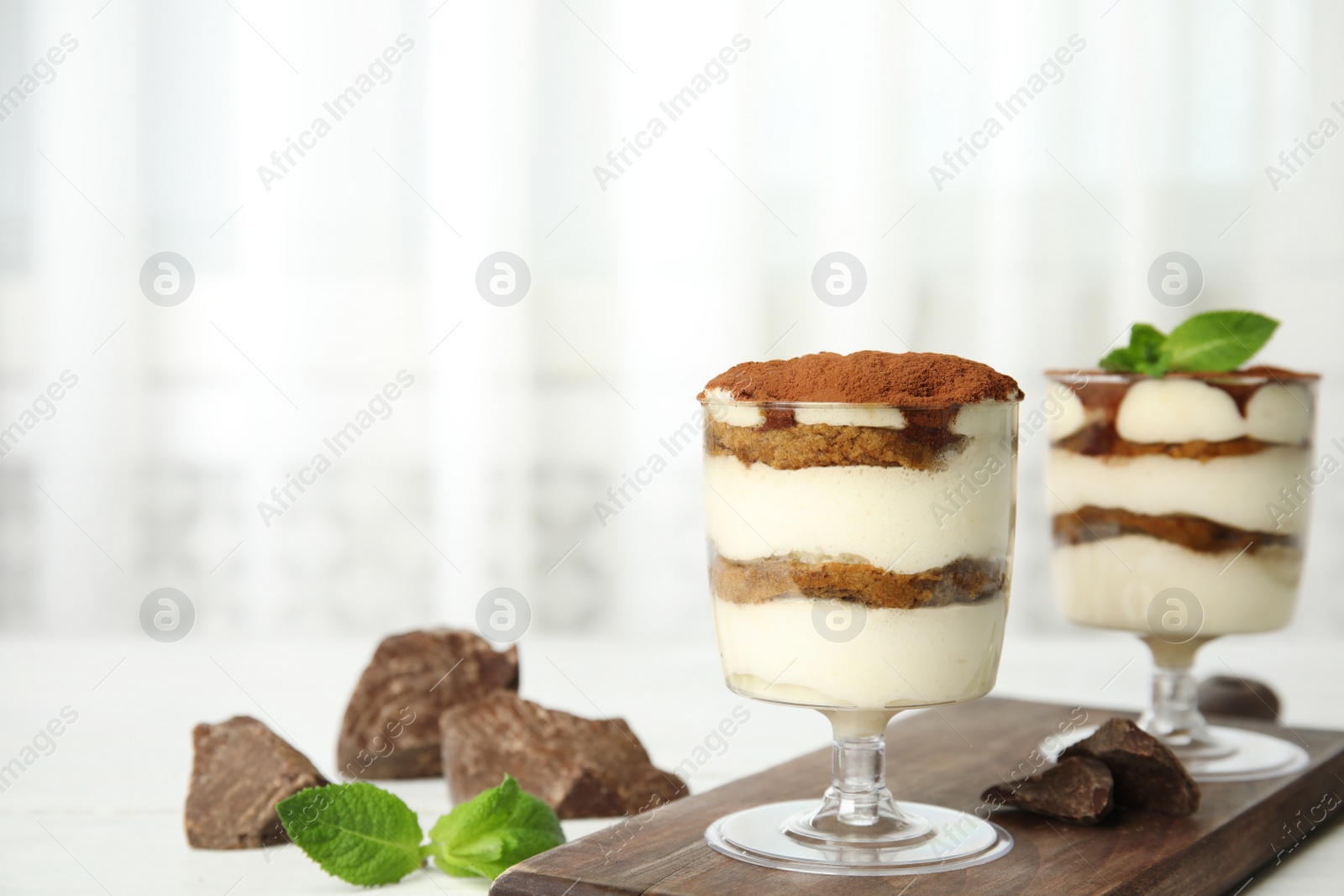 Photo of Composition with two glasses of tiramisu cake and chocolate on table, space for text