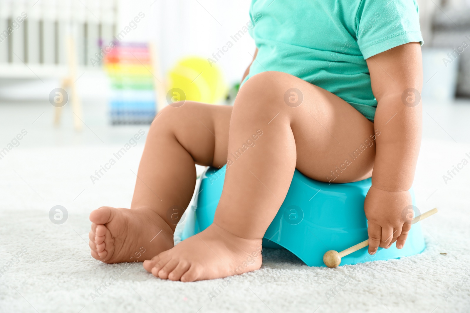 Photo of Little boy with wooden stick sitting on potty at home, closeup