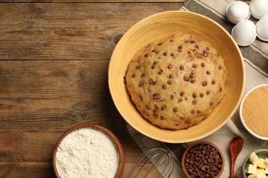 Bowl with dough and ingredients for cooking chocolate chip cookies on wooden table, flat lay. Space for text