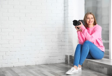 Female photographer with camera sitting on windowsill indoors