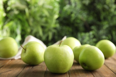 Photo of Fresh ripe green apples on wooden table against blurred background. Space for text