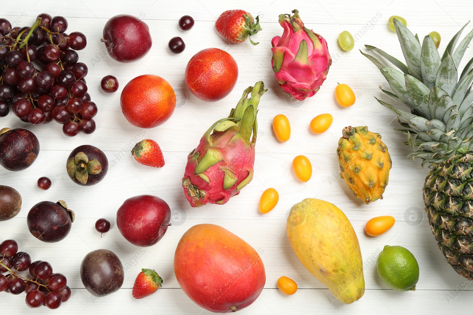 Photo of Many different delicious exotic fruits on white wooden table, flat lay