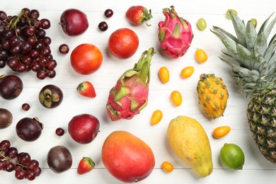 Photo of Many different delicious exotic fruits on white wooden table, flat lay