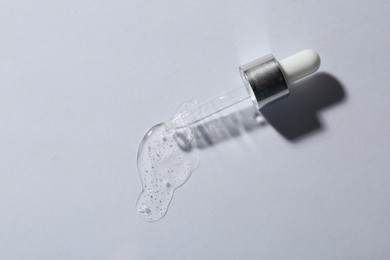 Pipette with cosmetic serum on white background, top view