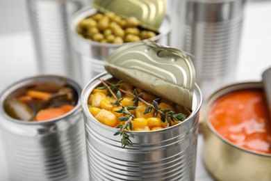 Open tin cans with corn kernels and different products closeup