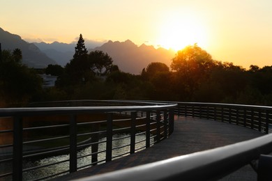 Bridge with metal handrails in park at sunset