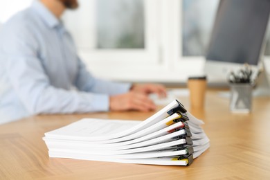 Photo of Man working at wooden table in office, focus on documents