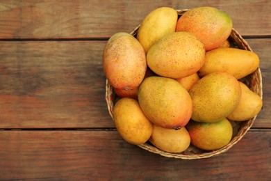 Delicious ripe juicy mangos on wooden table, top view. Space for text
