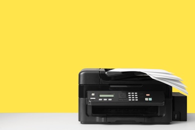 New modern printer with paper on yellow background. Space for text