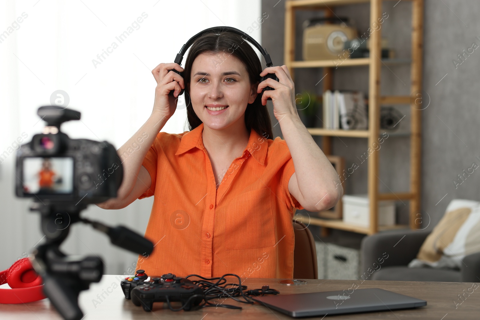 Photo of Smiling technology blogger wearing headphones while recording video at home