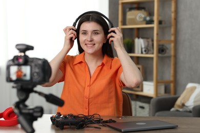 Smiling technology blogger wearing headphones while recording video at home